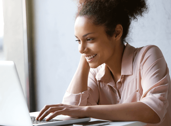 Close up portrait of a beautiful young woman smiling and looking at laptop screen