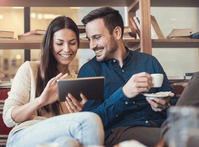 young couple having coffee looking at ipad